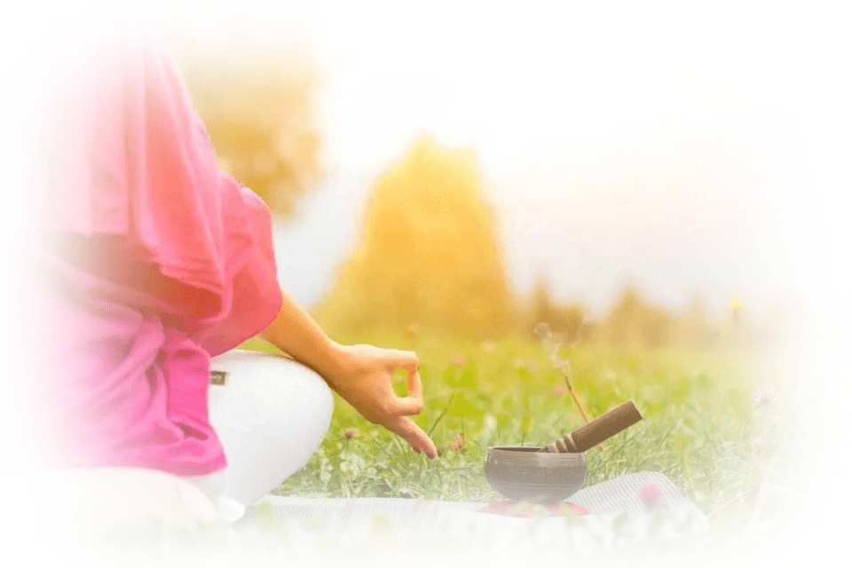 A person meditating outdoors with a singing bowl